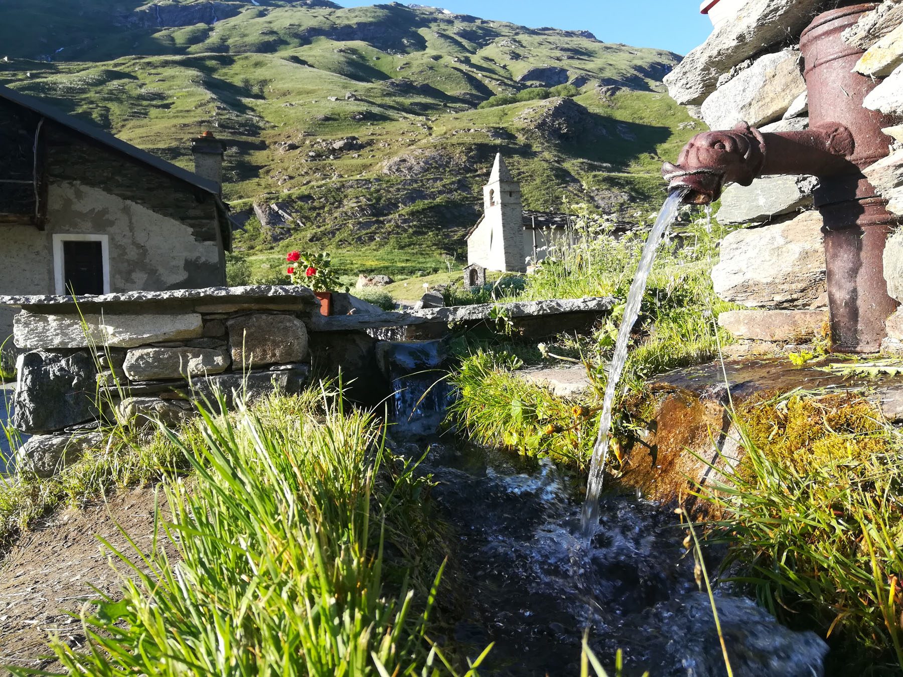 Mountain fountain and chapel in summer