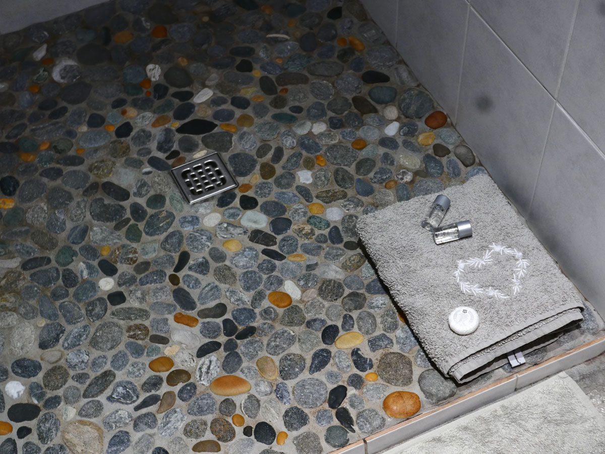 Serviette brodée sur le sol de douche en galets